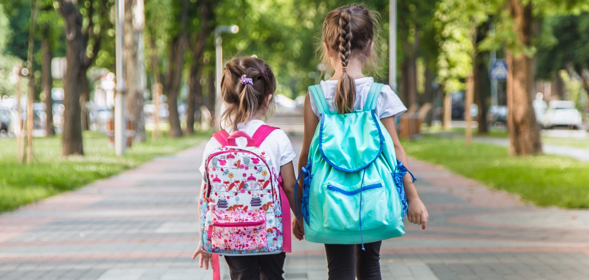 Back to school education concept with girl kids, elementary students, carrying backpacks going to class